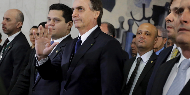 Brazil's President Jair Bolsonaro, center, arrives at the National Congress to deliver a proposal to overhaul Brazil's pension system, in Brasilia, Brazil, Wednesday, Feb. 20, 2019. Lawmakers received this week an anti-crime bill and a proposal to overhaul Brazil's pension system, the government's flagship reform. (AP Photo/Lucio Tavora)