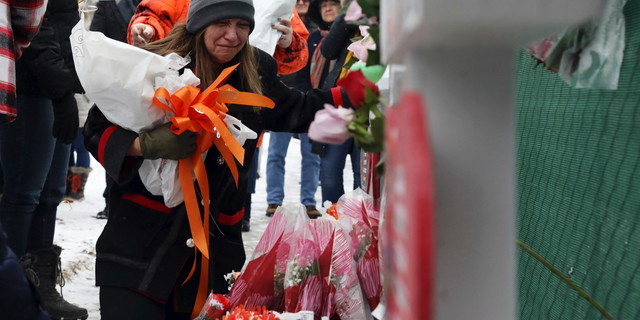 People pray at a makeshift memorial Sunday, Feb. 17, 2019, in Aurora, Ill., near Henry Pratt Co. manufacturing company where several were killed on Friday. Authorities say an initial background check five years ago failed to flag an out-of-state felony conviction that would have prevented a man from buying the gun he used in the mass shooting in Aurora. (AP Photo/Nam Y. Huh)