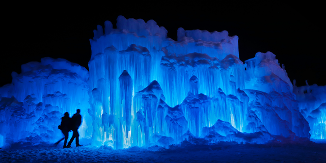 In this Saturday, Jan. 26, 2019 photo, a couple heads towards an entrance to a cavern at Ice Castles in North Woodstock, N.H. A team starts building massive walls in December to create a spectacular winter experience. (AP Photo/Robert F. Bukaty)