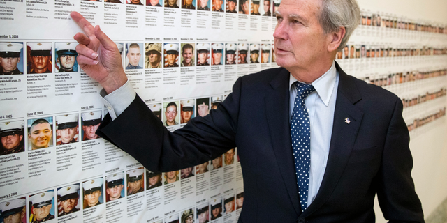 FILE - In this Oct. 25, 2017, file photo, U.S. Rep. Walter Jones, R-N.C., points at a photograph of Marine Sgt. Michael Edward Bits of Ventura, Calif., the first military funeral he and his wife attended, and one of the many pictures of soldiers killed this century based at Camp Lejeune, N.C., along a hallway leading to his office on Capitol Hill in Washington. Jones, a once-fervent supporter of the 2003 invasion of Iraq who later became an equally outspoken Republican critic of the war, died Sunday, Feb. 10, 2019, his 76th birthday. (AP Photo/Andrew Harnik, File)