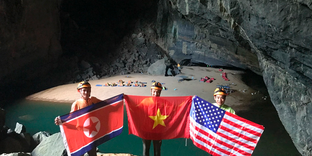 In this Monday, Feb. 15, 2019, drone image, cave explores pose with flags of North Korea, Vietnam and the U.S. in En cave in Quang Binh province, Vietnam. Vietnam will host the second summit between U.S. President Donald Trump and North Korean leader Kim Jong Un in Hanoi on Feb. 27-28. (Oxalis Adventure via AP)
