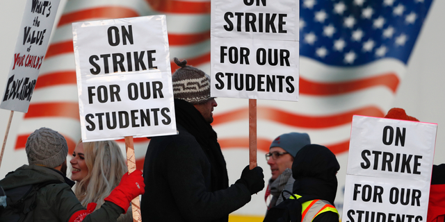 FILE - In this Feb. 11, 2019, file photo, teachers carry placards as they walk a picket line outside South High School in Denver. Oakland teachers say they will strike starting Thursday, Feb. 21. The union representing the 3,000 teachers announced the walkout Saturday, Feb. 16, making it the latest in a wave of educator activism that has swept the U.S. since last spring. (AP Photo/David Zalubowski, File)