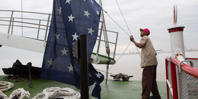 FILE - In this March 15, 2015 file photo, Dwayne McCornick, a deck hand on the Natchez steamboat for 16 years, raises the Union Jack naval flag on the Mississippi River in New Orleans. After nearly 17 years, United States Navy warships will return to flying the Union Jack, replacing the First Navy Jack flown in the wake of the Sept. 11 attacks.
News outlets report Chief of Naval Operations Adm. John Richardson issued an order Thursday, Feb. 21, 2019, calling for the blue banner with 50 white stars to return June 4 to commemorate World War II’s Battle of Midway. The Navy’s current maritime flag, the First Navy Jack, featured red and white stripes with a rattlesnake and the words “Don’t Tread On Me.” (AP Photo/Samantha Kaplan, File)