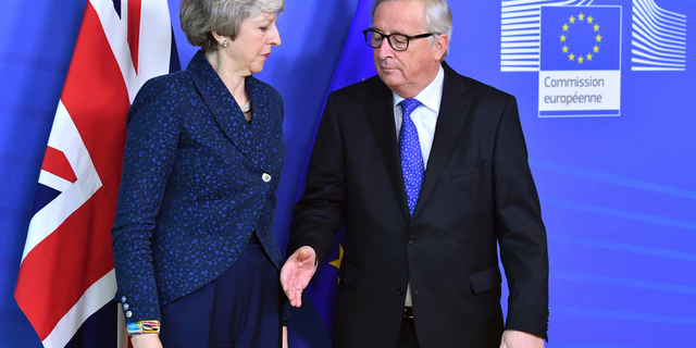 In this Thursday, Feb. 7, 2019 photo European Commission President Jean-Claude Juncker, right, prepares to shake hands with British Prime Minister Theresa May, left, before their meeting at the European Commission headquarters in Brussels, Belgium. EU Commission President Jean-Claude Juncker says he can't rule out that a delayed Brexit could mean the United Kingdom would participate in this spring's European Parliament election. (AP Photo/Geert Vanden Wijngaert, file)
