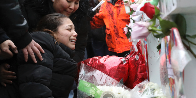 One of victim Vicente Juarez's daughter Diana Juarez cries at a makeshift memorial Sunday, Feb. 17, 2019, in Aurora, Ill., near Henry Pratt Co. manufacturing company where several were killed on Friday. Authorities say an initial background check five years ago failed to flag an out-of-state felony conviction that would have prevented a man from buying the gun he used in the mass shooting in Aurora. (AP Photo/Nam Y. Huh)