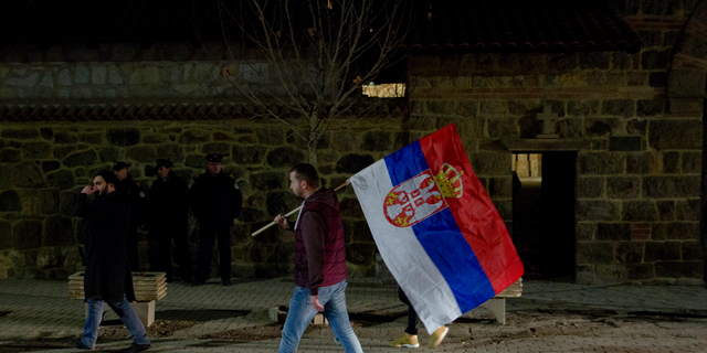 A protester carries a Serb flag and joins a demonstration against Serbian President Aleksandar Vucic in the town of Gracanica, Kosovo, on Feb. 9, 2019. (AP Photo/Visar Kryeziu)