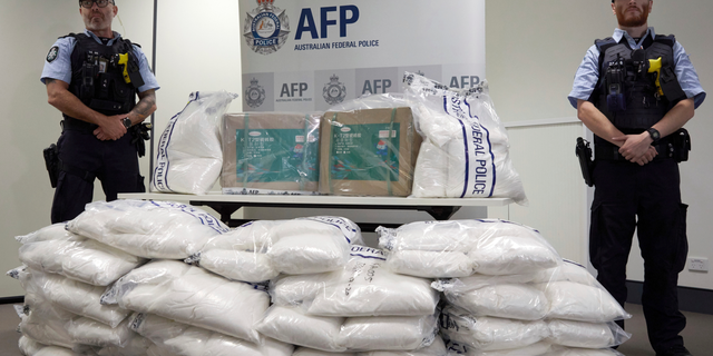 Police guard some of the 1.4 tons of seized ephedrine that is piled up during an Australian Federal Police press conference in Melbourne, Wednesday, Feb. 27, 2019. Australian authorities say they seized chemicals which could have been used to make one ton of methamphetamine and arrested four men in a joint operation with China. (Erik Anderson/AAP Image via AP)