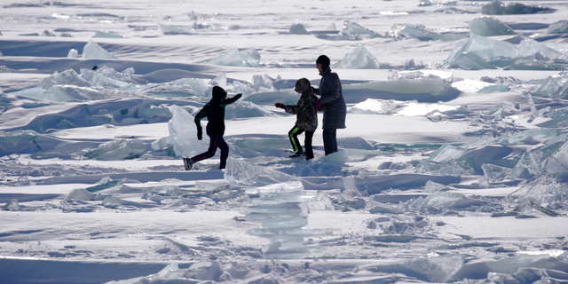 In this Friday, Feb. 22, 2019, photo, people play on the Ice on Lake Superior, starting to pack in along the shore near Duluth, Minn., and attracting explorers and ice fishermen out on to the lake. Access to the mainland ice caves remain CLOSED. Ice continues to move around quite a bit. Over the last few days, open water has been visible from Meyers Beach as well as near Eagle Island. This ice is typically poor quality ice, which reacts poorly to movement due to weak bonding along the fractures. (Brian Peterson/Star Tribune via AP)