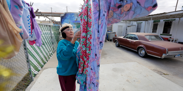 In this Tuesday, Jan. 22, 2019, photo, Mickie Subia gathers her laundry at her home in El Paso, Texas. Subia lives less than a block away from a border barrier that runs along the Texas-Mexico border in El Paso. (AP Photo/Eric Gay)