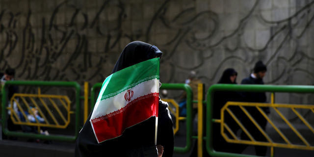FILE - In this Feb. 11, 2016 file photograph, an Iranian woman holds the national flag during a rally commemorating the 37th anniversary of the Islamic revolution, in Tehran, Iran. Iran's 1979 Islamic Revolution initially inspired both Islamic militants and Islamists across the Mideast. They saw the revolution as the starting gun in a competition to push out the strongman Arab nationalism that had taken hold across the Middle East. However, analysts say Iran's push to back militants in the wider Mideast and Saudi Arabia's efforts to mobilize the Sunni world against the Shiite power would turn many away. (AP Photo/Ebrahim Noroozi, File)