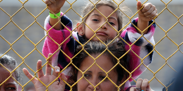 Six-year-old Daniela Fernanda Portillo Burgos sits on the shoulders of her mother, Iris Jamilet, 39, as they look out through the fence of a immigrant shelter in Piedras Negras, Mexico, Tuesday, Feb. 5, 2019. A caravan of about 1,600 Central American migrants camped Tuesday in the Mexican border city of Piedras Negras, just west of Eagle Pass, Texas. The governor of the northern state of Coahuila described the migrants as "asylum seekers," suggesting all had express intentions of surrendering to U.S. authorities. (Jerry Lara/The San Antonio Express-News via AP)