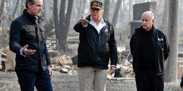 FILE - In this Nov. 17, 2018, file photo, President Donald Trump talks with then Gov.-elect Gavin Newsom, left, and as California Gov. Jerry Brown listens during a visit to a neighborhood impacted by the wildfires in Paradise, Calif. California Gov. Gavin Newsom says the Trump administration is engaging in "political retribution" by trying to take back $3.5 billion granted for the state's high-speed rail project. The Democratic governor says President Donald Trump is reacting to California suing over Trump's emergency declaration to pay for a wall along the U.S.-Mexico border. (AP Photo/Evan Vucci, File)