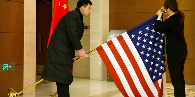 Chinese staffers adjust a U.S. flag before the opening session of trade negotiations between U.S. and Chinese trade representatives at the Diaoyutai State Guesthouse in Beijing, Thursday, Feb. 14, 2019. (AP Photo/Mark Schiefelbein, Pool)