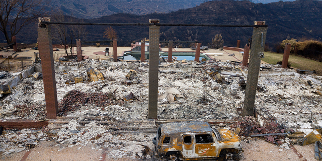 FILE - In this Dec. 3, 2018 file photo, a vehicle rests in front of a home leveled by the Camp Fire in Paradise, Calif. Pacific Gas & Electric says its equipment may have ignited the 2018 Camp Fire, which killed 86 people and destroyed an entire town in Northern California. The embattled utility said Thursday, Feb. 28, 2019, it’s taking a $10.5 billion charge for claims connected to the Camp Fire in its fourth quarter earnings.(AP Photo/Noah Berger, File)