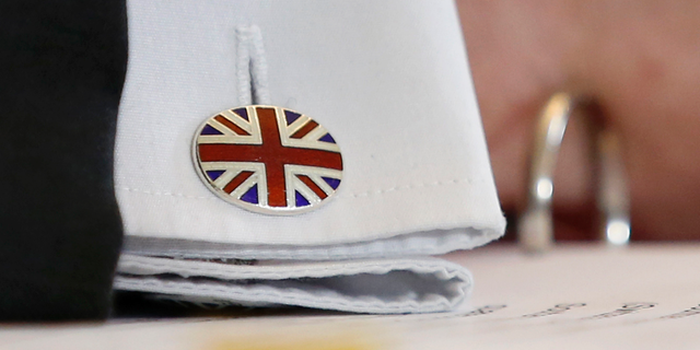A cuff button of British Secretary of State for International Trade Liam Fox shows the Union Jack, after signing a trade agreement with Swiss Federal Councillor Guy Parmelin (not pictured) in Bern, Switzerland, Monday, Feb. 11, 2019. Parmelin and Fox signed a bilateral trade agreement regulating relations between the two countries after the Brexit. Because of the customs treaty with Switzerland, the agreement also applies to Liechtenstein. (Peter Klaunzer/Keystone via AP)