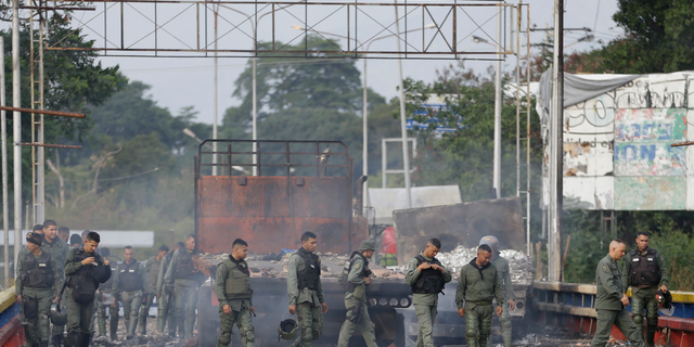 Venezuelan Bolivarian National Guard officers inspect trucks torched over the weekend during clashes with anti-government demonstrators trying to move aid across the Francisco de Paula Santander International Bridge in Urena, Venezuela, Tuesday, Feb. 26, 2019. Starting on Saturday, security forces on Venezuela's borders with Colombia and Brazil fired tear gas and buckshot on activists as they blocked emergency medical and food kits from crossing into Venezuela.