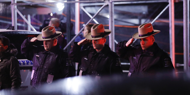 Officers salute a procession as the remains of slain Detective Brian Simonsen are removed from Jamaica Hospital Medical Center Tuesday, Feb. 12, 2019, in the Queens borough of New York. The NYPD detective and a NYPD sergeant were shot while responding to an armed robbery at a T-Mobile store in Queens. (AP Photo/Kevin Hagen)