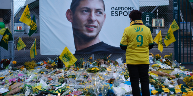FILE - In this Wednesday, Jan. 30, 2019, file photo, a Nantes soccer team supporters stops by a poster of Argentinian player Emiliano Sala and reading "Let's keep hope" outside La Beaujoire stadium before the French soccer League One match Nantes against Saint-Etienne, in Nantes, western France.