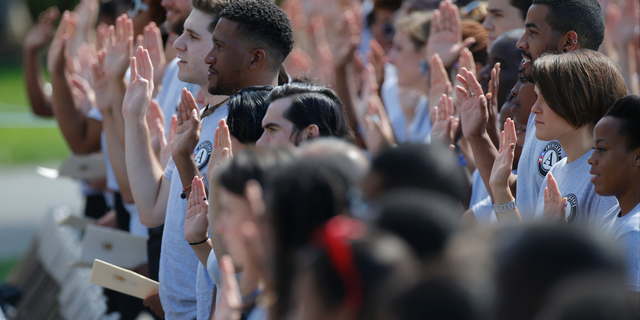 FILE - In this Sept. 12, 2014 file photo, AmeriCorps volunteers take a pledge as President Barack Obama and former President Bill Clinton mark the 20th anniversary of AmeriCorps, which promotes volunteerism and community service, on the South Lawn at the White House in Washington. Hundreds of Teach for America alumni are slamming the educator placement program for telling members to cross the picket line during a potential teacher strike in Oakland, California, or risk losing thousands of dollars at the end of their service. In partnership with the AmeriCorps, Teach for America members can apply for an education award at the end of their service to help pay off student loans. An AmeriCorps spokeswoman couldn't immediately provide comment but said striking is prohibited. (AP Photo/Charles Dharapak, File)
