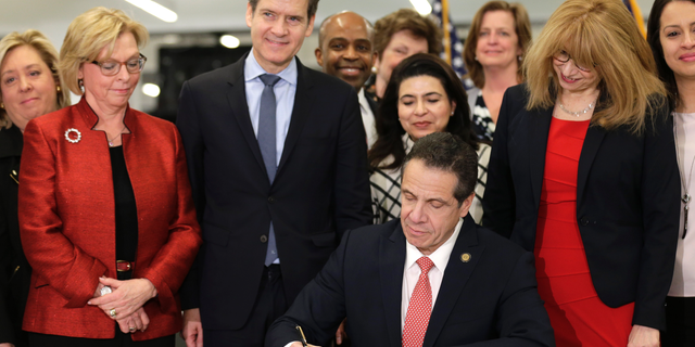 New York Gov. Andrew Cuomo, center, signs the Child Victims Act in New York, Thursday, Feb. 14, 2019. Cuomo has signed into law long-sought legislation that extends the statute of limitations so sexual abuse victims can have more time to seek criminal charges or file lawsuits. (AP Photo/Seth Wenig)