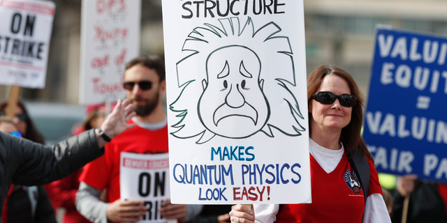 An instructor carries a placard as she marches to Denver Public Schools headquarters to deliver Valentine Day cards Wednesday, Feb. 13, 2019, in Denver. Teachers walked off their jobs Monday, the first strike by teachers in Denver in 25 years. (AP Photo/David Zalubowski)