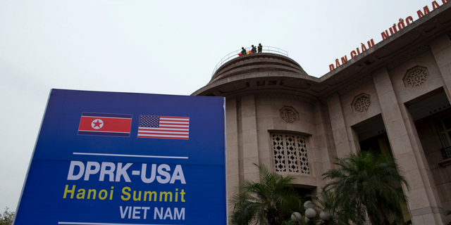 Vietnamese soldiers watch from a top of a building neighboring Government Guesthouse and the Metropole hotel next to a poster featuring upcoming summit between the U.S. and North Korea in Hanoi, Vietnam, Sunday, Feb. 24, 2019. The second summit between U.S President Donald Trump and North Korean leader Kim Jong Un will take place in Hanoi on Feb. 27 and 28. (AP Photo/Gemunu Amarasinghe)