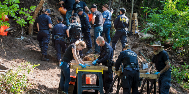 In this July 5, 2018, file photo, members of the Toronto Police Service excavate the back of a property in Toronto during an investigation in relation to Bruce McArthur.