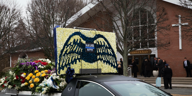 A limousine that is part of the funeral procession for Det. Brian Simonsen, is parked in front of the Church of St. Rosalie in Hampton Bays, N.Y., Wednesday, Feb. 20, 2019. Simonsen, with the New York City Police Department, was killed by friendly fire Feb. 12 as he and six other officers opened fire on a robbery suspect who police say was pointing at them what appeared to be a handgun. (AP Photo/Mark Lennihan)