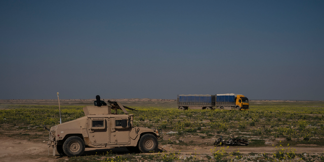 A U.S.-backed Syrian Democratic Forces (SDF) Humvee stands by as a truck that is part of a convoy evacuating hundreds out of the last territory held by Islamic State militants, passes in Baghouz, eastern Syria, Wednesday, Feb. 20, 2019. The evacuation signals the end of a week long standoff and opens the way to U.S.-backed Syrian Democratic Forces (SDF) recapture the territory. (AP Photo/Felipe Dana)