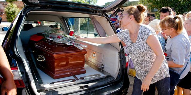 People leave flowers on Emiliano Sala's coffin at the cemetery in Santa Fe, Argentina, Saturday, Feb. 16, 2019.