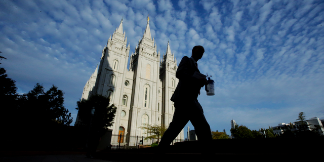 FILE - In this Sept. 14, 2016, file photo, a man walks past the Salt Lake Temple, a temple of The Church of Jesus Christ of Latter-day Saints, at Temple Square in Salt Lake City. Parents of Mormon missionaries will be able to hear their children's voices a lot more often under new rules announced Friday, Feb. 15, 2019, that allow the proselytizing youngsters to call home every week instead of only twice a year. (AP Photo/Rick Bowmer, File)