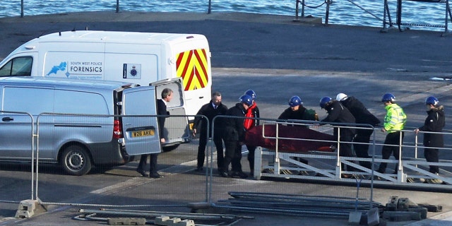 A stretcher carrying a body is removed from the Geo Ocean III specialist search vessel docked in Portland, England, Thursday Feb. 7, 2019.