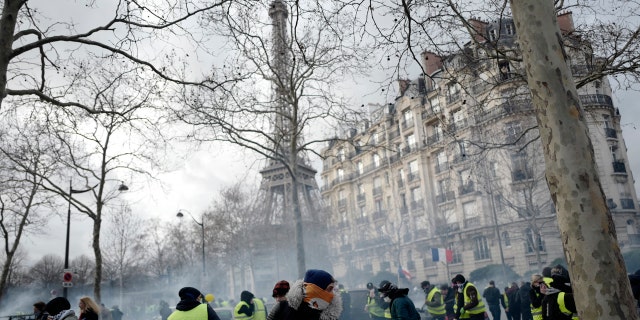Yellow vest protesters run away from tear gas fired by riot police as they keep pressure on French President Emmanuel Macron's government, for the 13th straight weekend of demonstrations, during a demonstration in Paris, France, Saturday, Feb. 9, 2019.