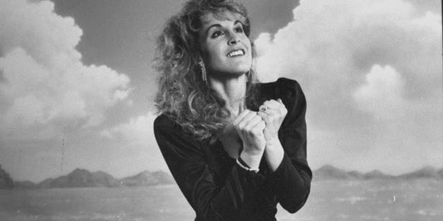 Actress Jodi Benson posing in front of an ocean scene backdrop as the voice of the mermaid Ariel for the movie "The Little Mermaid. "