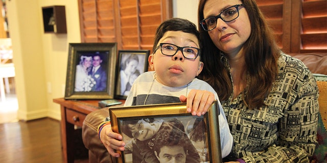 Sergio Cardenas holds a picture of himself with his father Gustavo as he sits on the lap of his mother Maria Elena Cardena, Gustavo's wife, at their home in Katy, Texas, Friday, Feb. 15, 2019. Gustavo, a Citgo executive, has been held in detention by the Venezuelan government along with five other Citgo employees since November of 2017, but their preliminary hearing has been postponed 12 times, leaving the families to question whether their loved ones are being held as pawns in a high-stakes political negotiation.