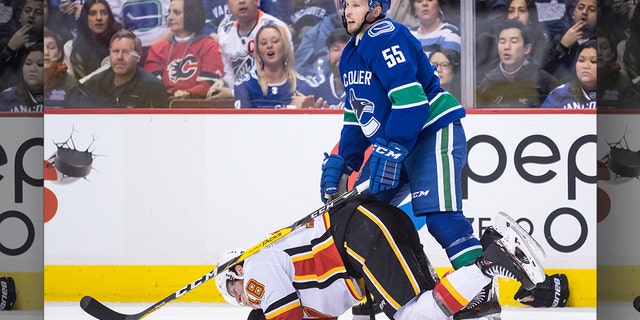 Calgary Flames' James Neal, bottom, holds his mouth after taking a high stick to the face from Vancouver Canucks' Alex Biega (55) and losing teeth during the third period of an NHL hockey game Saturday, Feb. 9, 2019, in Vancouver, British Columbia. (Darryl Dyck/The Canadian Press via AP)