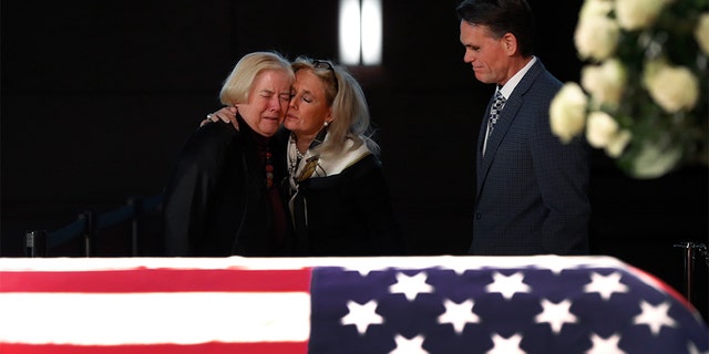 Rep. Debbie Dingell, D-Mich., center, consoled former Rep. Candice Miller, R-Mich., as Macomb County executive Mark Hackel, right, looked on at the casket of former Rep. John Dingell, lying in repose in Dearborn on Monday. (AP Photo/Paul Sancya)