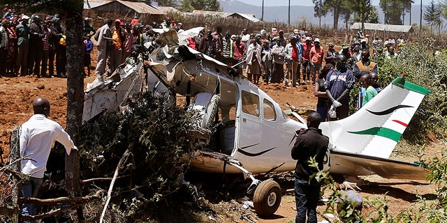 Rescuers and bystanders gather near the wreckage of a Cessna 206 light aircraft that crashed with its Kenyan pilot and four foreign passengers in Londiani Kenya.