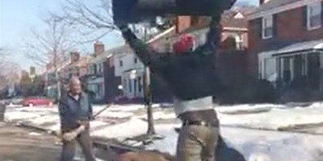 Bystanders tried to use objects such as a stick and garbage bag to get the dog off the mailman, to no avail.