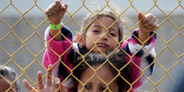 Six-year-old Daniela Fernanda Portillo Burgos sits on the shoulders of her mother, Iris Jamilet, 39, as they look out through the fence of a immigrant shelter in Piedras Negras, Mexico, Tuesday, Feb. 5, 2019.