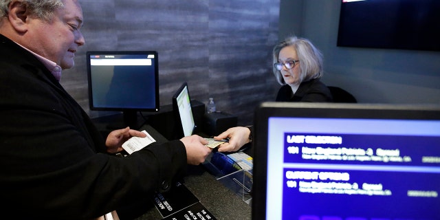 In this Monday, Jan. 28, 2019 photo, Rhode Island state Rep. William O'Brien places a $100 bet at Twin River Casino in Lincoln, R.I., on the New England Patriots NFL football team to win over the Los Angeles Rams in Super Bowl 53.