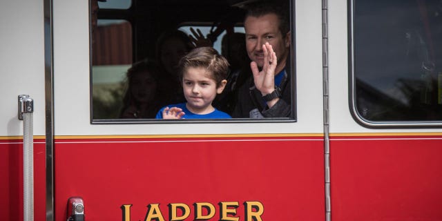 Owen Coulter, 5, and his dad, Darin, who is a firefighter ride home in a firetruck after he made a miraculous 56-day recovery at Dell Children's Hospital in Austin, Texas.