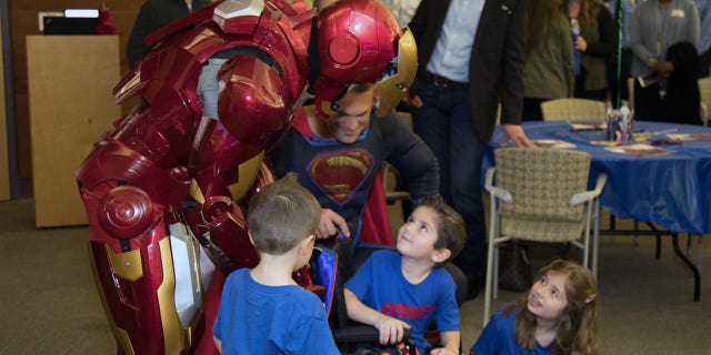 Owen Coulter, 5, celebrates his recovery with superheroes, Ironman and Superman, from the Austin Police Department.