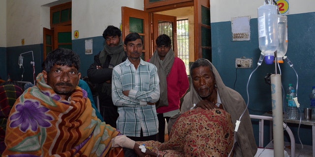 Two men who consumed bootleg alcohol, sit on a hospital bed as relatives look on, in Saharanpur, northern state of Uttar Pradesh, India February 11, 2019. REUTERS/Stringer - RC1A90540A20