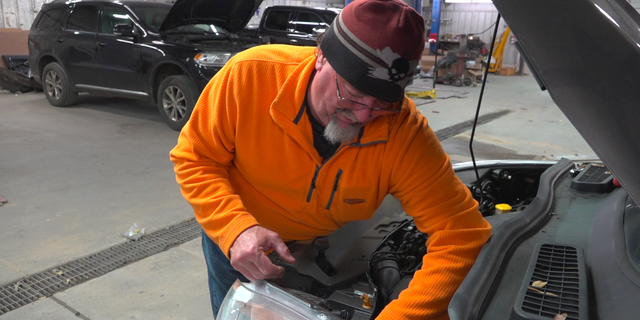 Ronnie Harwell changes a headlight.