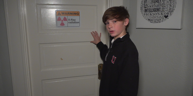 Jackson Oswalt,14, shows off the sign on the door of his home laboratory warning of X-ray radiation.
