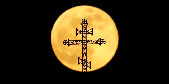 The full moon rises behind a steeple with crosses of an Orthodox church in Minsk, Belarus, Tuesday, Feb. 19, 2019.