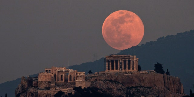 The moon rises over the Parthenon on the ancient Acropolis Hill in Athens, Greece, Tuesday, Feb. 19, 2019.