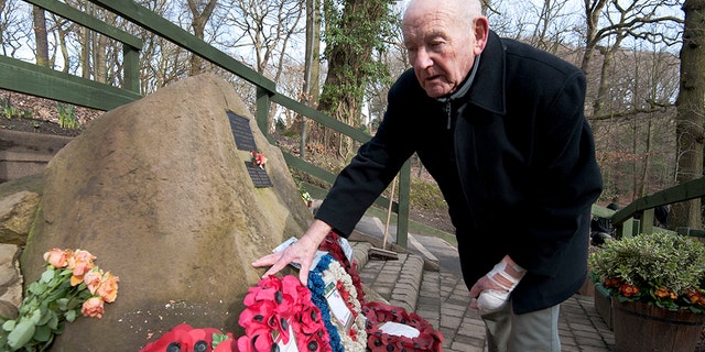 Tony Foulds tends to a memorial honouring 10 U.S. airmen who died in a plane crash in Endcliffe Park, Sheffield, England, Wednesday, Feb. 13, 2019. Foulds was just a kid running around in the park on Feb. 22, 1944 when a U.S. Air Force crew decided to crash and die rather than take the chance of hitting them. He's dreamed of honoring them for decades.