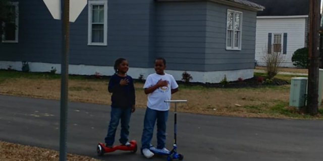 Two boys reciting the pledge of allegiance in front of a North Carolina fire station.